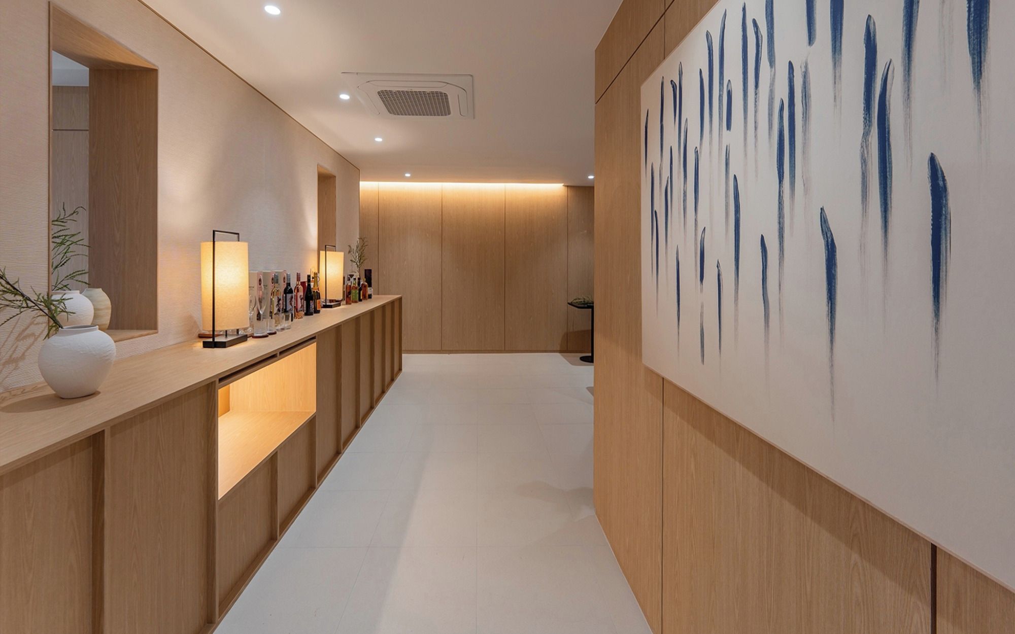 A modern interior with a reception desk, wooden paneling, and a large abstract painting.