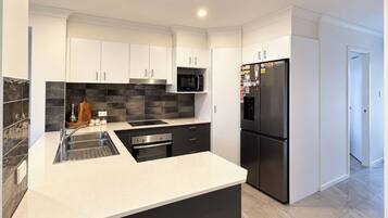 A modern kitchen with white cabinetry, a black refrigerator, and a black microwave.