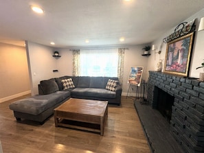 A living room with a sectional sofa, a coffee table, a fireplace, and a painting on the wall. - Long Beach Gem - Close To Entertainment, Beaches (Long Beach)