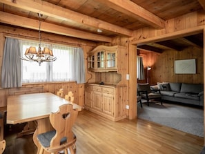 A wooden cabin interior with a dining table, chairs, a cabinet, a sofa, and a chandelier. - Mountain View Vals by Interhome (Vals)