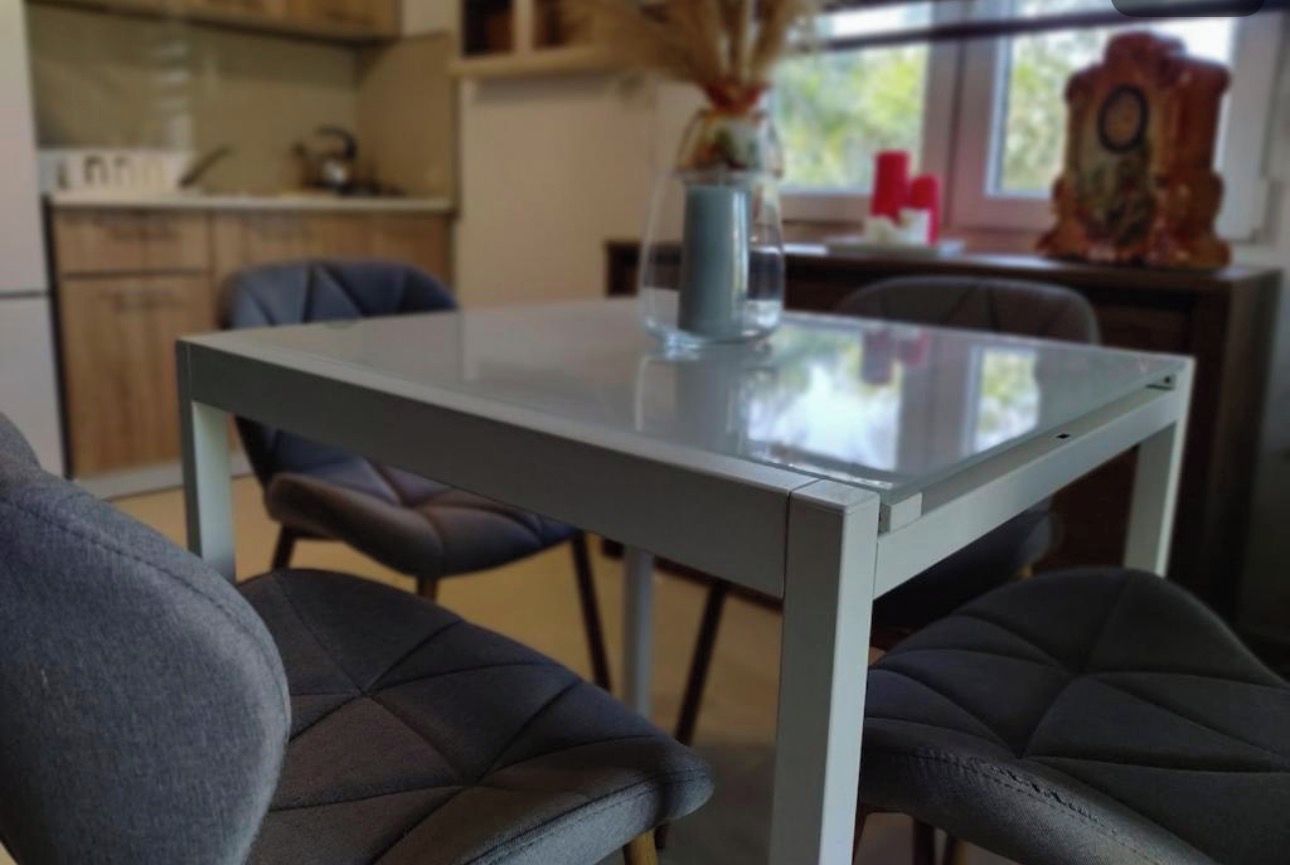 A dining area with a glass-top table and four upholstered chairs.