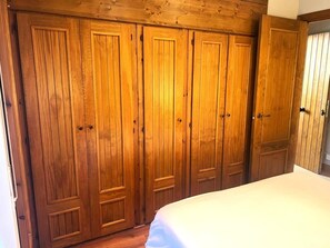 A bedroom with a large wooden wardrobe, a bed, and a wooden ceiling. - Nice apartment in La Molina (La Molina)