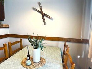 A dining area with a table set for two, a vase with greenery, a candle, and a bottle of perfume. - Nice apartment in La Molina (La Molina)