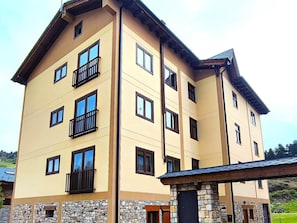 A multi-story building with balconies and a stone base. - Nice apartment in La Molina (La Molina)