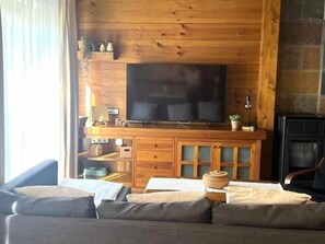 A living room with a large flat-screen TV, wooden cabinets, a fireplace, and a sofa. - Nice apartment in La Molina (La Molina)