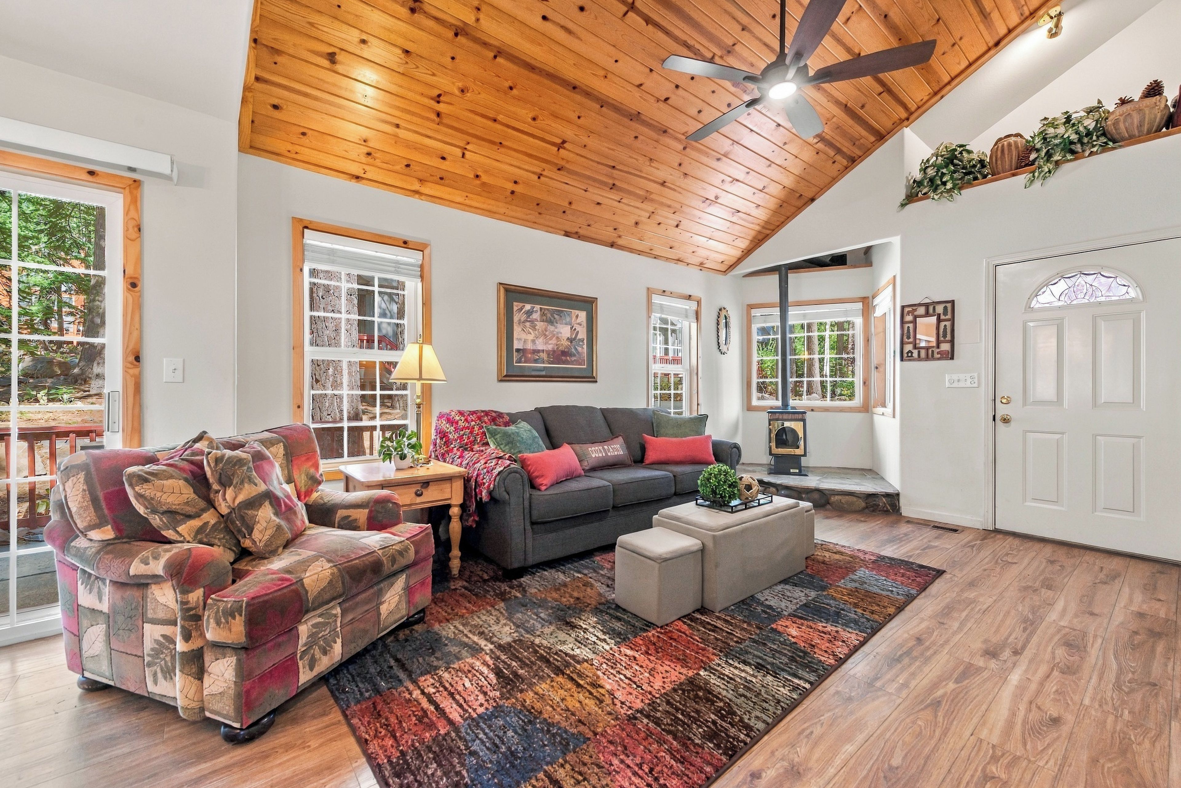 A cozy living room with a wooden ceiling, a sofa, a chair, and a coffee table.