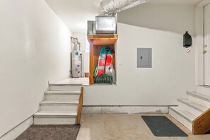 A stairway leading to a room with a water heater, a fire extinguisher, and a door with a mailbox. - Little Pinecone Retreat close to Rec Center (Truckee)