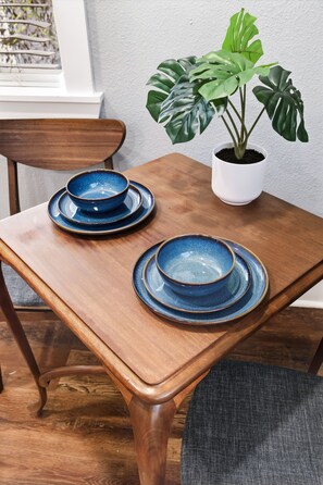 Ein Holztisch mit zwei blauen Keramiktellern und einer Blumentopfpflanze.