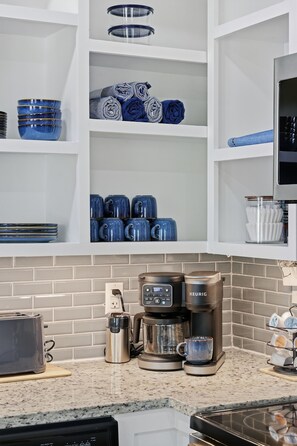 Eine Küche mit einer Kaffeemaschine, einem Toaster und verschiedenen Küchenutensilien auf der Arbeitsfläche.