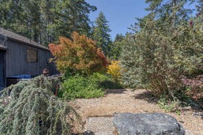 Eine rustikale Holzhütte, umgeben von verschiedenen Bäumen und Sträuchern, von denen einige sich im Herbstlaub zeigen.