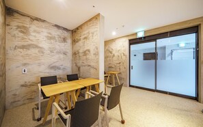 Una sala de conferències amb paret de marbre, taula gran i cadires.