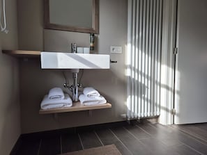 A bathroom with a white sink, two towel racks, a mirror, and a radiator. - B&BCosy (Lievegem)