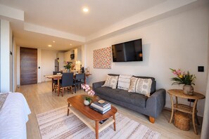 Una sala de estar moderna con sofá, mesa de centro y televisor montado en la pared.