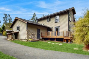 A two-story house with a stone foundation, a front porch, and a covered entryway. - Little River Zen - Gardens, BBQ & Pet Friendly (Little River)