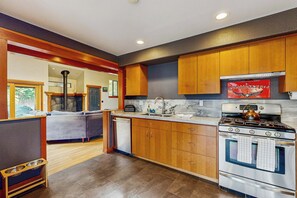 A modern kitchen with wooden cabinets, a stainless steel stove, and a marble countertop. - Little River Zen - Gardens, BBQ & Pet Friendly (Little River)