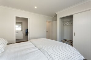 Une chambre à coucher avec un lit, un dressing et une salle de bain avec un miroir.