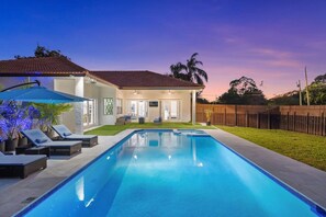 Ein Wohngebiet-Schwimmbad mit Liegestühlen und einer überdachten Terrasse.
