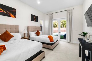 Ein Hotelzimmer mit zwei Betten, einem Schreibtisch, einem Fernseher und Blick ins Freie.