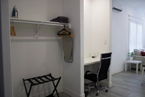 A room with a white desk, a black office chair, a hanging clothes rack, and a white radiator. - East Downtown Loft + Workspace (Houston)
