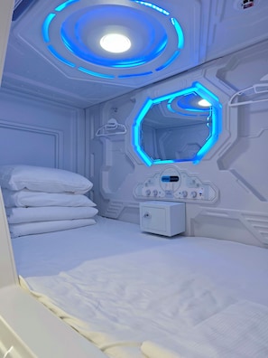Una habitació amb un llit, un panell de control i una làmpada circular.