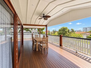 Eine überdachte Terrasse im Freien mit Tisch und Stühlen, einem Deckenventilator und Blick auf die Umgebung.