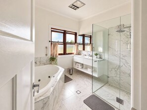 Ein modernes Badezimmer mit einer Badewanne, einer Duschkabine und einem Waschtisch mit Spiegel.