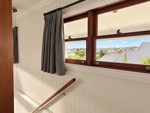 Ein Zimmer mit Fenster, Holzjalousien und Blick auf eine Wohngegend.