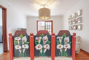 Un couloir orné d’un panneau mural décoratif représentant des lys calla, d’un lustre et d’une porte donnant sur l’extérieur.