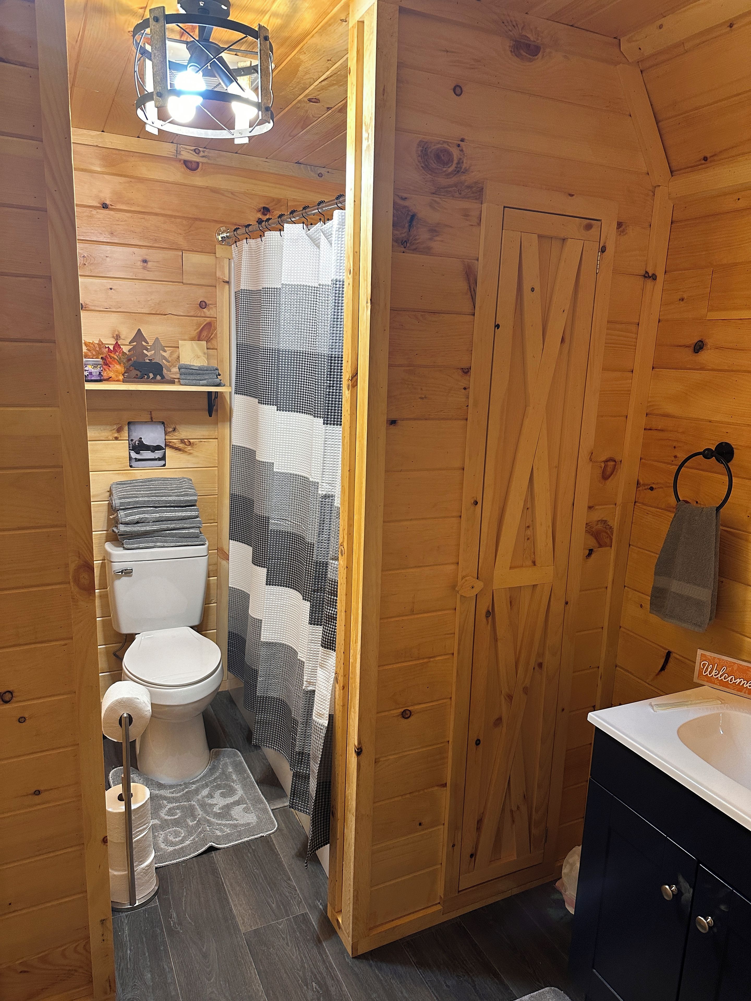 Ein Badezimmer mit Holzeinrichtung, einer Toilette, einer Duschkabine und einem Waschbecken.