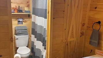 Ein Badezimmer mit Holzeinrichtung, einer Toilette, einer Duschkabine und einem Waschbecken.