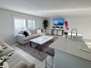 A modern living room with a sofa, coffee table, and a TV mounted on the wall. - East Downtown Loft + Full Kitchen (Houston)