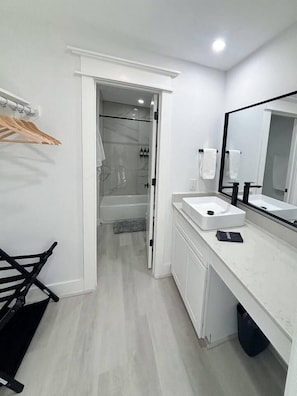 A modern bathroom with a shower, a sink, and a mirror. - East Downtown Loft + Full Kitchen (Houston)