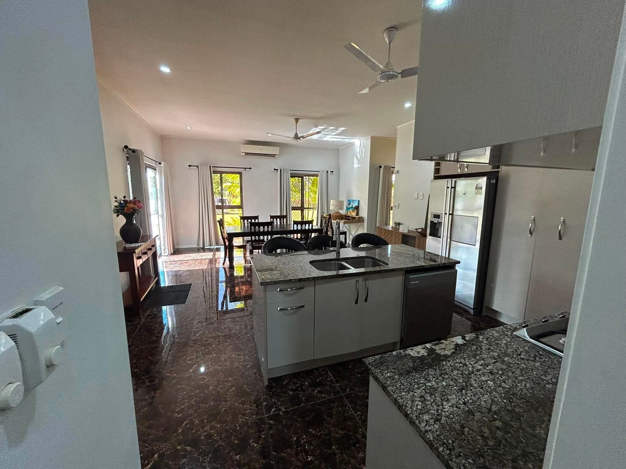 A modern kitchen with a central island, stainless steel appliances, and a dining area with a view.
