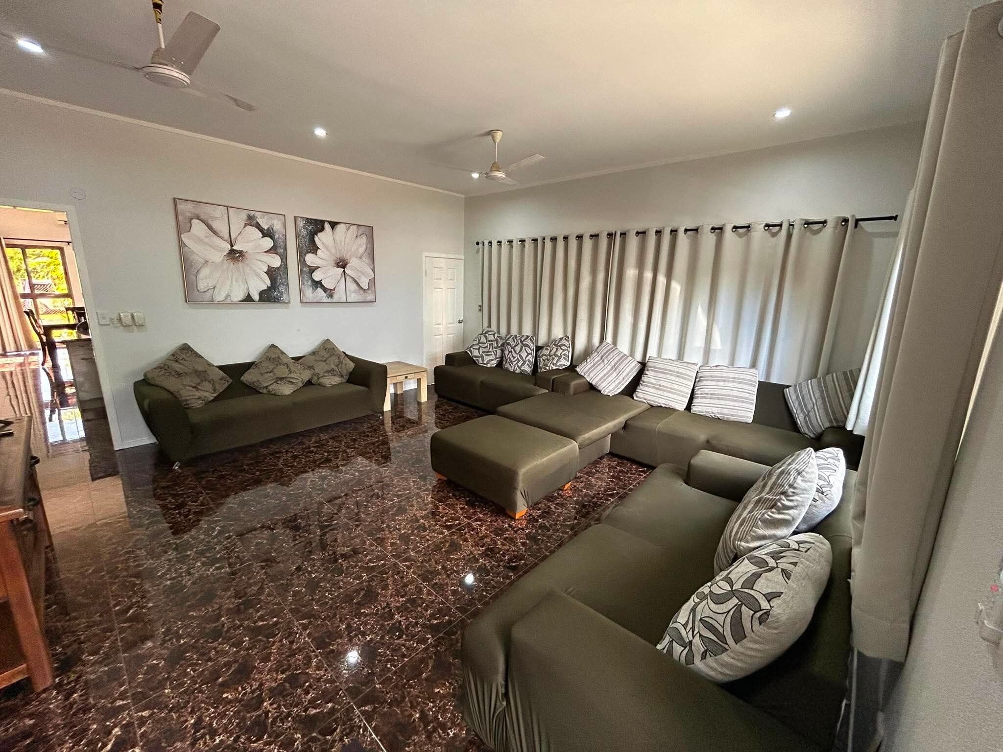 Uma sala de estar moderna com sofá de canto, mesa de centro e piso de mármore.
