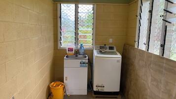 A small laundry room with a washing machine, a dryer, and a yellow bucket on the floor.
