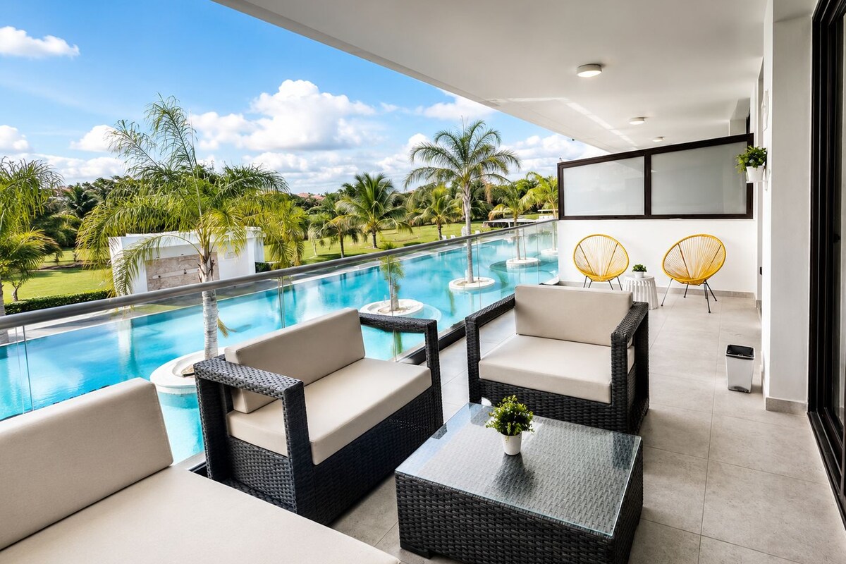 Un área lounge exterior moderna con piscina, mobiliario de mimbre y vistas a un paisaje tropical.