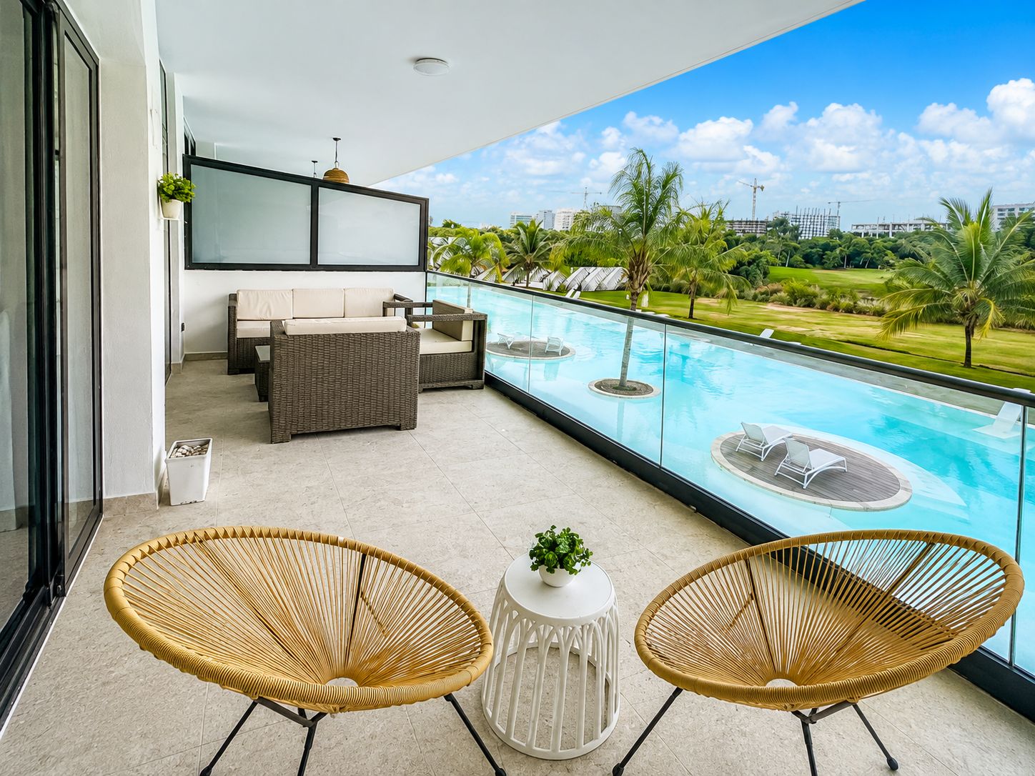Varanda com piscina, mobiliário de vime e vista para um campo de golfe.