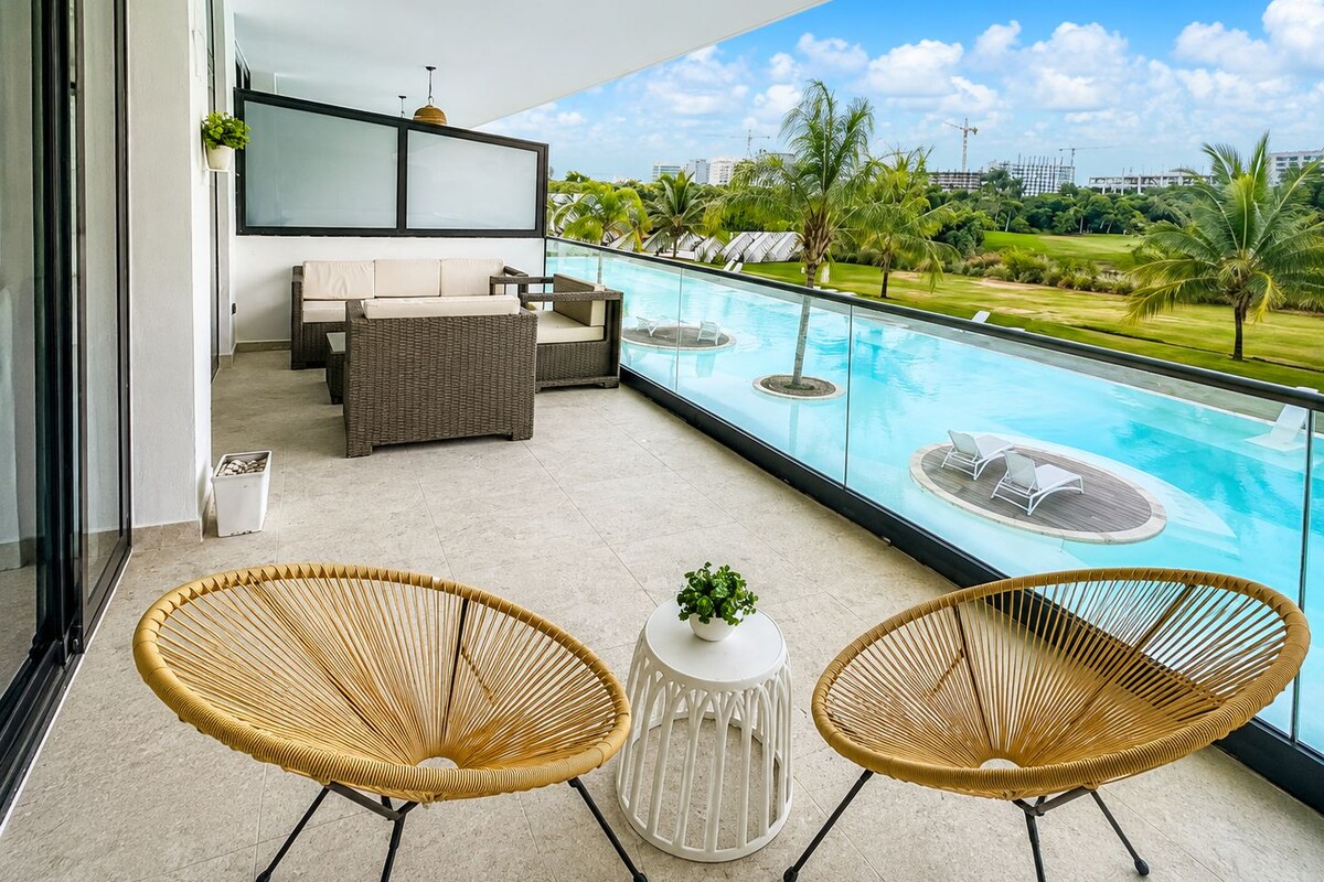 Un balcón con piscina, mobiliario de mimbre y vistas a un campo de golf.