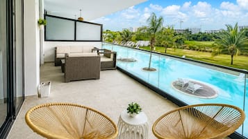 Varanda com piscina, mobiliário de vime e vista para um campo de golfe.