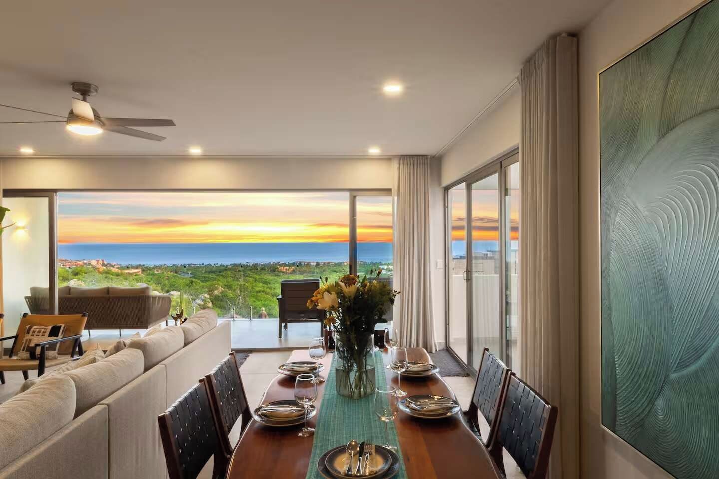 Un coin repas avec vue sur la mer, un ventilateur de plafond et une table mise pour le repas.