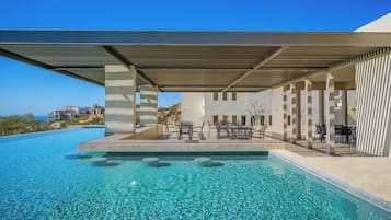 A swimming pool with clear water, surrounded by outdoor seating and a covered area.