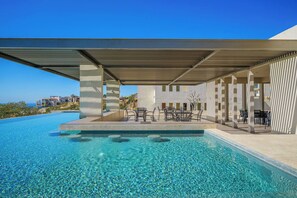 A swimming pool with clear water, surrounded by outdoor seating and a covered area. - Casa Estrella | 4BD Villa | Private Rooftop Pool (Cabo San Lucas)