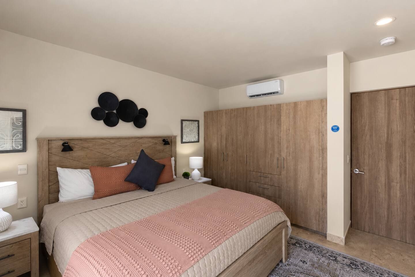 Ein Schlafzimmer mit einem Bett, Nachttischen, einem Kleiderschrank und einer Wand-Klimaanlage.