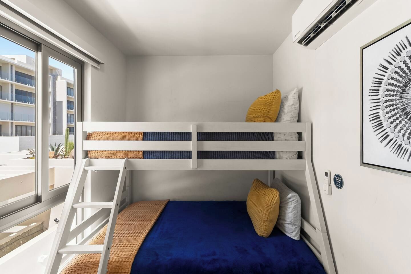 A bunk bed room with a window, a framed artwork, and a thermostat on the wall.