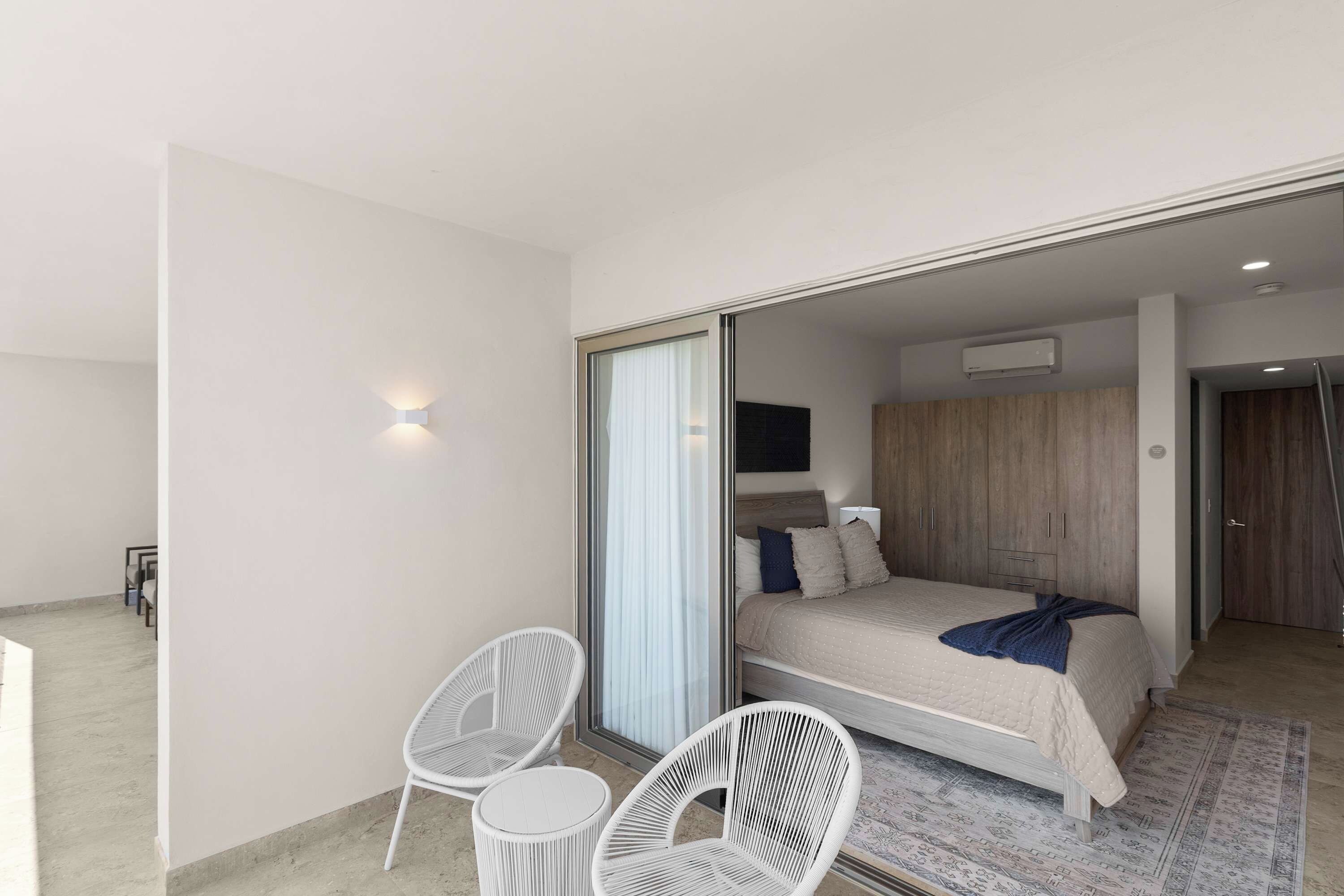 A modern bedroom with a bed, a chair, a small table, and a wardrobe.