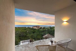 A balcony with two wicker chairs, a small table, and a potted plant. - Casa Estrella | 4BD Villa | Private Rooftop Pool (Cabo San Lucas)