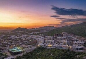 A residential area with modern buildings, a swimming pool, and a hilly landscape in the background. - Casa Estrella | 4BD Villa | Private Rooftop Pool (Cabo San Lucas)
