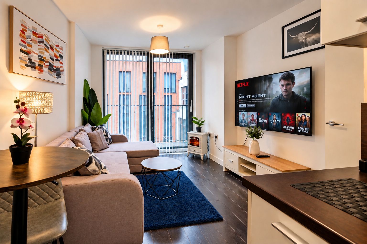 Un salon moderne avec un canapé, une table basse, un téléviseur diffusant la série « The Night Agent », et une grande fenêtre équipée de stores.
