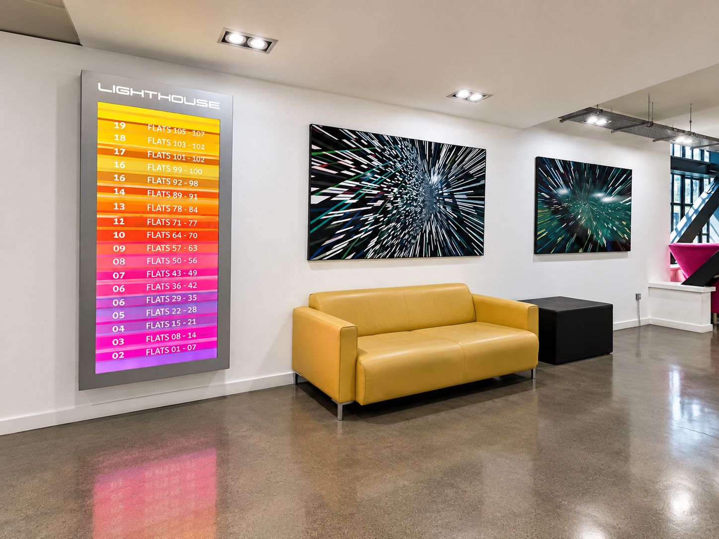 Ein modernes Interieur mit einem gelben Sofa, abstrakter Kunst an den Wänden und einem beleuchteten Schild mit Zimmernummern und -typen.