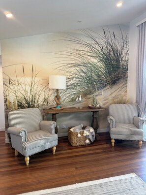 A room with two striped armchairs, a wooden coffee table, and a wall mural. - Relaxing getaway with the family  on the water. (South Stradbroke)
